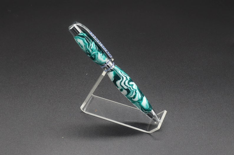 Full side view of green and white (aka seafoam green) princess pen with blue crystals and chrome hardware on clear pen stand.