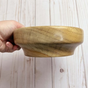 Camphor bowl with wide opening and narrower base - side view showing one side of grain pattern in the wooden bowl, being held