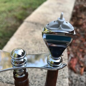 Close-up of eucalyptus shaving set with brush, stand, and razor handle sitting outside on a paver stone with grass in the background - focusing on Mach3 Razor head