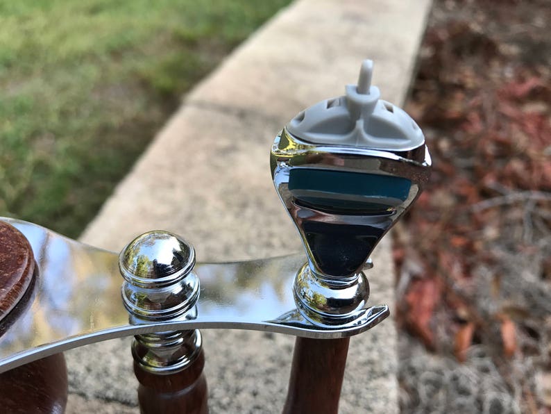 Close-up of eucalyptus shaving set with brush, stand, and razor handle sitting outside on a paver stone with grass in the background - focusing on Mach3 Razor head