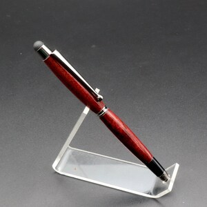 Side view of Purpleheart stylus pen with gun metal hard in clear pen stand over black background