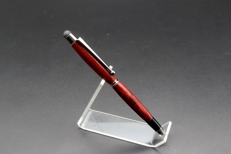 Side view of Purpleheart stylus pen with gun metal hard in clear pen stand over black background