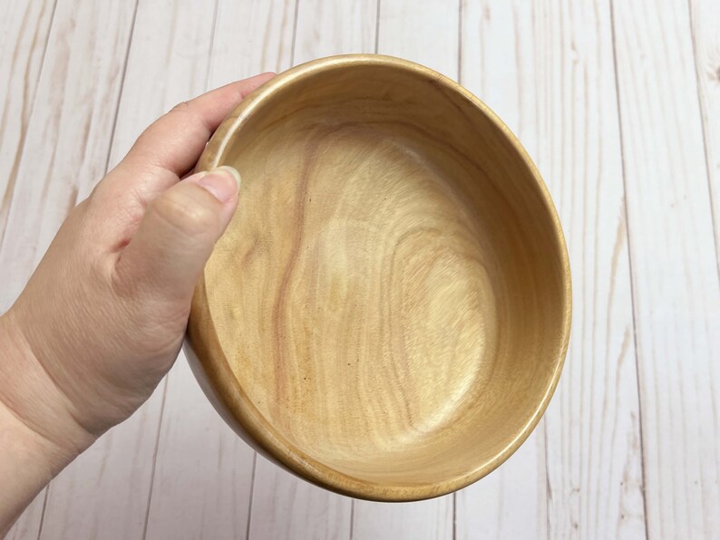 Shallow bowl made from camphor wood - being held at an angle to show more of the inside of the bowl