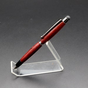 Side view of Purpleheart stylus pen with gun metal hard in clear pen stand over black background