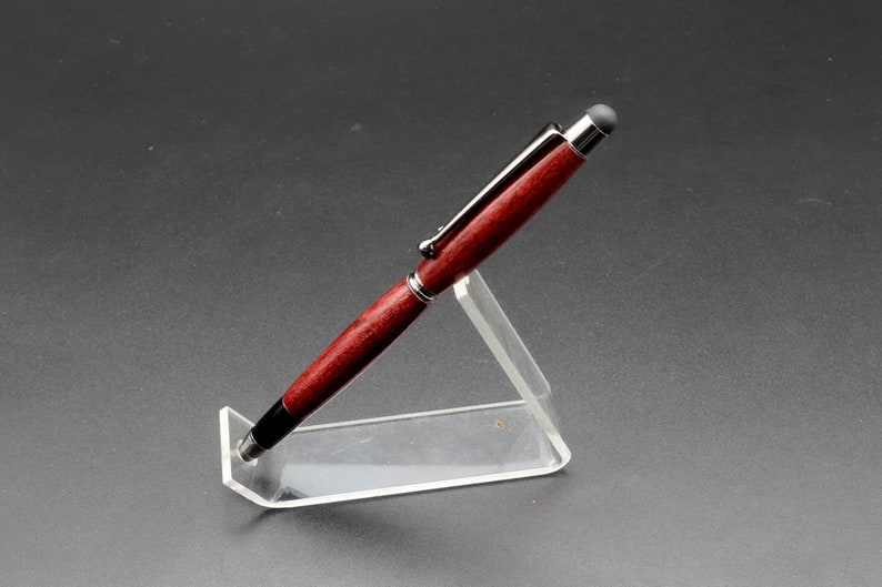 Side view of Purpleheart stylus pen with gun metal hard in clear pen stand over black background