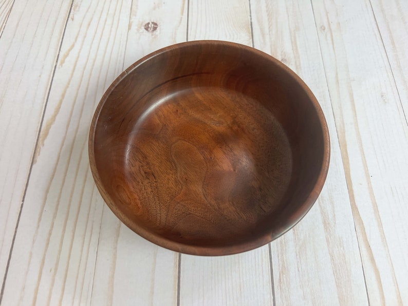 Indian Rosewood wooden bowl on woodgrain table - top down view showing inside of the bowl