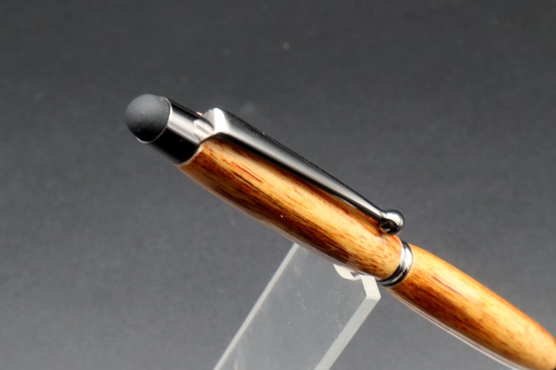 Close up view of stylus tip for Canarywood stylus pen with gun metal hardware in pen stand over black background