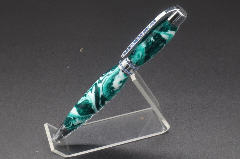 Full side view of green and white (aka seafoam green) princess pen with blue crystals and chrome hardware on clear pen stand.