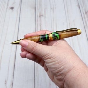 Holding olive wood and resin twist pen with satin gold hardware