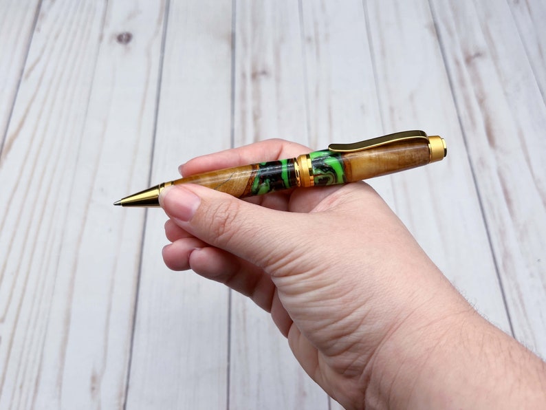 Holding olive wood and resin twist pen with satin gold hardware