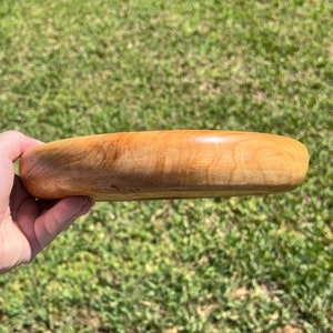 Shallow bowl made of Cypress wood - being held in natural light, side view