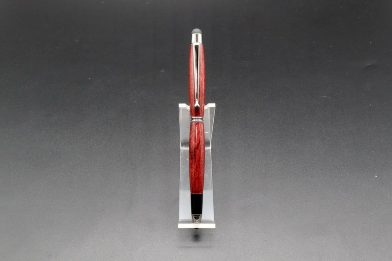 Front view of Purpleheart stylus pen with gun metal hard in clear pen stand over black background