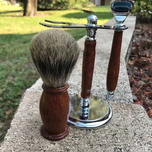 Eucalyptus shaving set with brush, stand, and razor handle sitting outside on a paver stone with grass in the background
