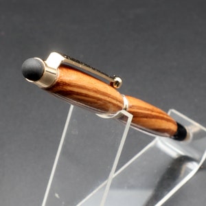 Top view of stylus tip from Zebrawood stylus pen with 24kt gold hardware in clear pen stand over black background