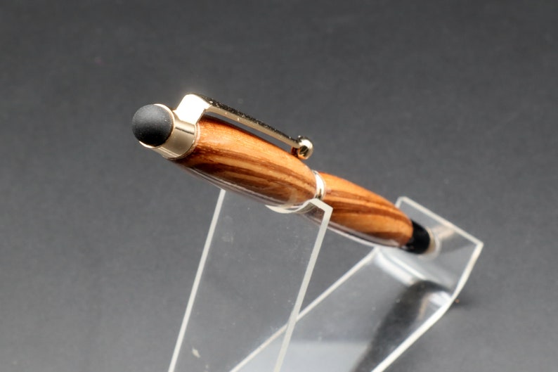 Top view of stylus tip from Zebrawood stylus pen with 24kt gold hardware in clear pen stand over black background