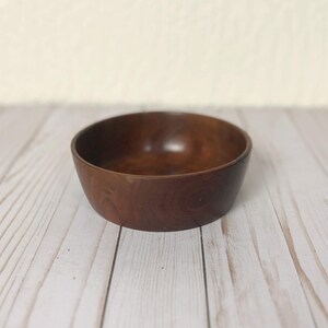 Indian Rosewood wooden bowl on woodgrain table - angle view showing side and part of inside of bowl