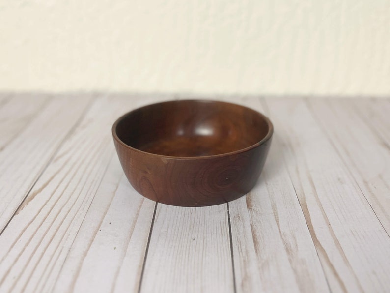 Indian Rosewood wooden bowl on woodgrain table - angle view showing side and part of inside of bowl