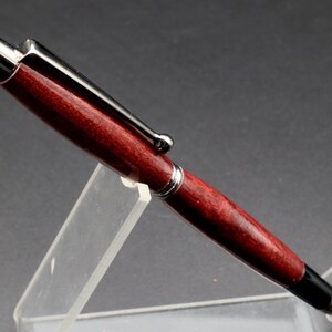 Close-up side view of Purpleheart stylus pen with gun metal hard in clear pen stand over black background