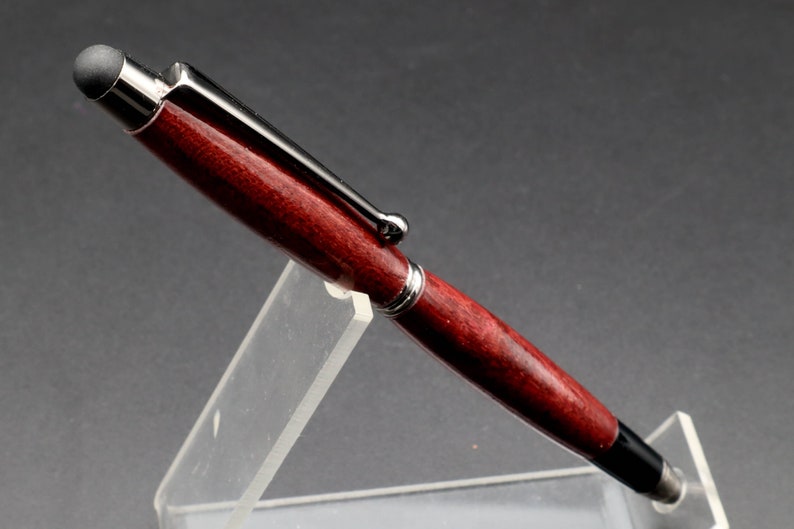 Close-up side view of Purpleheart stylus pen with gun metal hard in clear pen stand over black background