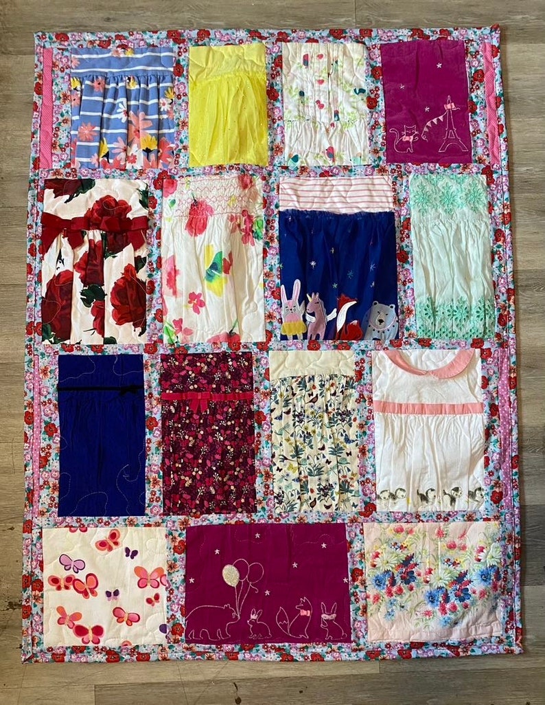 May include: A patchwork quilt with a variety of floral and animal prints. The quilt is made up of 12 squares, each with a different design. The quilt is pink, blue, white, red, and yellow.