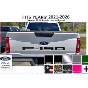 May include: A white Ford F-150 truck tailgate featuring black F-150 lettering. Text reads FITS YEARS: 2021-2026 (except 2024 Pro-Access tailgate). Includes a Ford Official Licensed Product badge and a color chart showing gloss, matte, chrome, gray, green, flag, camo, carbon fiber, and hot pink options.