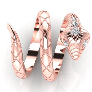 Puede incluir: Un anillo de serpiente en oro rosa con un cuerpo en espiral y un diseño texturizado de patrón de diamantes. La cabeza de la serpiente está decorada con tres piedras redondas transparentes en fila vertical y dos piedras en los lados.