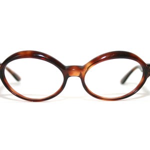 Peut inclure: Lunettes de forme ovale avec un motif écaille de tortue. Les montures sont de couleur marron chaud et les verres sont transparents. Ces lunettes ont un design classique et vintage, adapté à un usage quotidien.