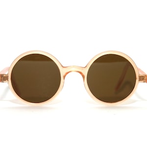 May include: Round, peach-colored sunglasses with brown lenses.