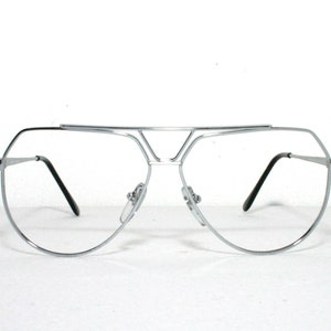 Peut inclure: Lunettes de style aviateur argentées avec un double pont et des montures octogonales.