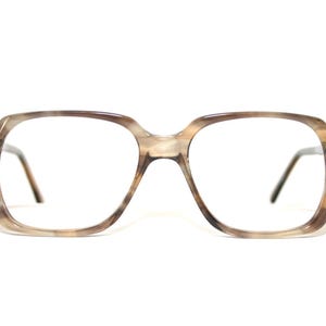 May include: Square-framed eyeglasses with a marbled, light brown and tan pattern. The glasses have a thick frame and dark brown temples. The lenses are clear. The overall style is vintage.