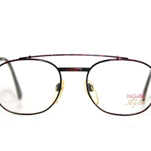 May include: A pair of red and black metal eyeglasses with a thin metal bridge and round lenses.