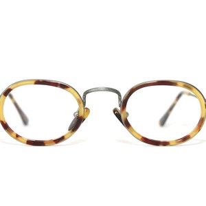 May include: Tortoise shell oval-shaped eyeglasses with a silver metal frame.