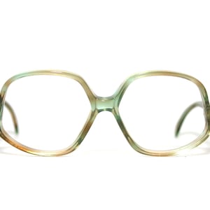 Könnte beinhalten: Vintage Brille mit einem einzigartigen sechseckigen Rahmendesign. Die Rahmen sind eine Mischung aus Grün-, Braun- und Klartönen mit einem subtilen Farbverlauf. Die Bügel sind dunkelbraun.