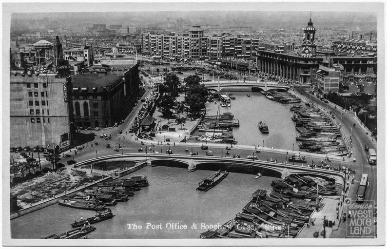 May include: A black and white vintage postcard showing a view of the Post Office and Soochow Creek in Shanghai, China. The postcard features a bridge over the creek, with boats docked on either side. The Post Office building is visible in the background.