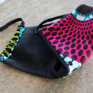 May include: A black fabric face mask with a pink and black patterned fabric lining. The mask has elastic ear loops.