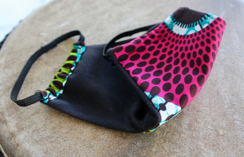 May include: A black fabric face mask with a pink and black patterned fabric lining. The mask has elastic ear loops.