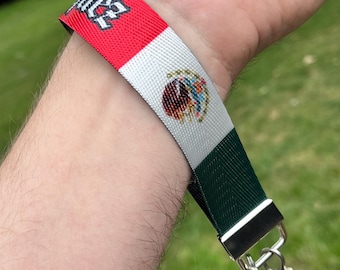May include: A red, white, and green lanyard with the Mexican flag and the text "Mexico" printed on it. The lanyard has a silver clasp and a silver chain attached to it.