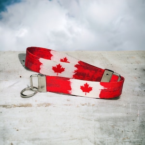 May include: A red and white lanyard with a Canadian flag design and a silver key ring.