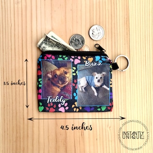 May include: A black zippered pouch with a paw print design. The pouch has two photos of dogs, one named "Teddy" and the other named "Buzz". The pouch measures 4.5 inches wide and 3.5 inches tall.