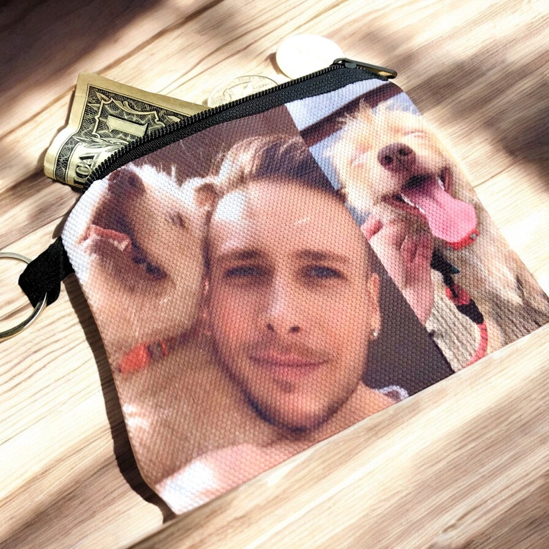 May include: A zippered pouch with a photo of a man and two dogs. The photo is printed on a fabric material. The pouch is black with a zipper.