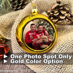 Op de afbeelding: Een ronde gouden kerstbal met een centrale ronde foto van twee personen in rode truien met een kleine hond. De kerstbal heeft een gouden dop en een ophanglus. De tekst op de afbeelding luidt: One Photo Spot Only, Gold Color Option.