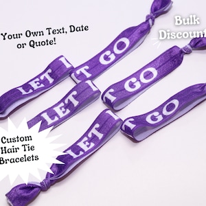 May include: Purple elastic hair ties with the text "Let It Go" printed in white. The hair ties are arranged in a starburst pattern on a white background. The text "Custom Hair Tie Bracelets" is printed in a white starburst shape below the hair ties.
