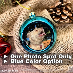 Op de afbeelding: Een glanzende blauwe, bolvormige kerstbal met een ronde foto-inzet van een lichtgekleurde hond met de tong uit de bek. Het ornament heeft een gouden ophanglus aan de bovenkant. De tekst op de afbeelding luidt: One Photo Spot Only, Blue Color Option.