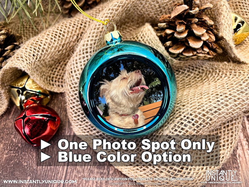 Op de afbeelding: Een glanzende blauwe, bolvormige kerstbal met een ronde foto-inzet van een lichtgekleurde hond met de tong uit de bek. Het ornament heeft een gouden ophanglus aan de bovenkant. De tekst op de afbeelding luidt: One Photo Spot Only, Blue Color Option.