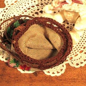May include: A brown beaded purse with a crocheted trim and a beige fabric lining. The purse is open and the lining is visible.
