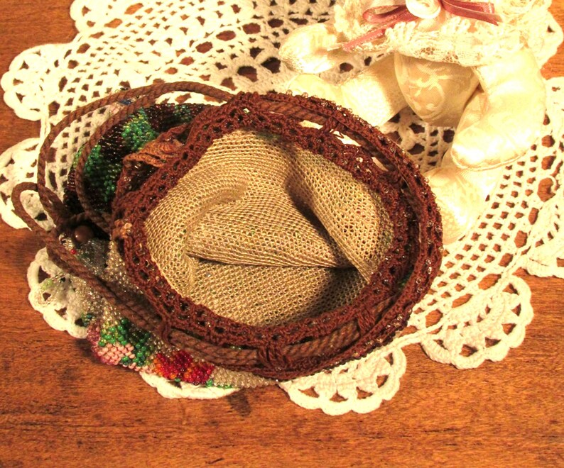 May include: A brown beaded purse with a crocheted trim and a beige fabric lining. The purse is open and the lining is visible.