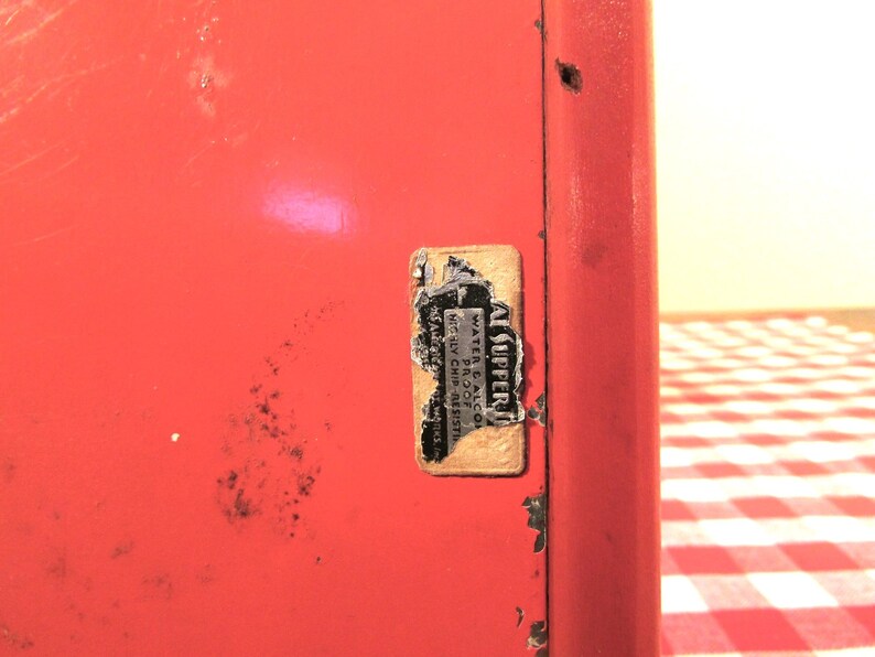 Puede incluir: Una caja de metal roja con una pegatina blanca que dice "AL SUPPERI WATER-PROOF OIL-PROOF MADE IN CHICAGO, ILL."