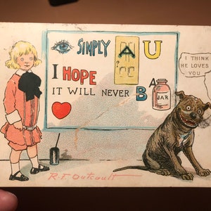Puede incluir: Postal vintage con una ni&ntilde;a y un perro. La ni&ntilde;a lleva un vestido rosa y un lazo negro. El perro es marr&oacute;n y blanco con una gran sonrisa. La postal tiene un mensaje que dice "Simply AU I Hope It Will Never B A Jar I Think He Loves You".