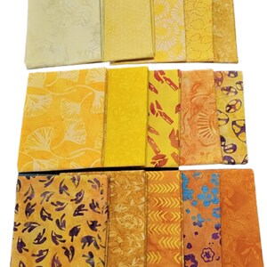 May include: A collection of 16 fabric squares in various shades of yellow and orange with different patterns. The fabrics feature designs such as ginkgo leaves, flowers, and geometric shapes.