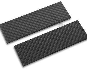 May include: Two black carbon fibre scales for knife making. The scales are rectangular and have a woven pattern.